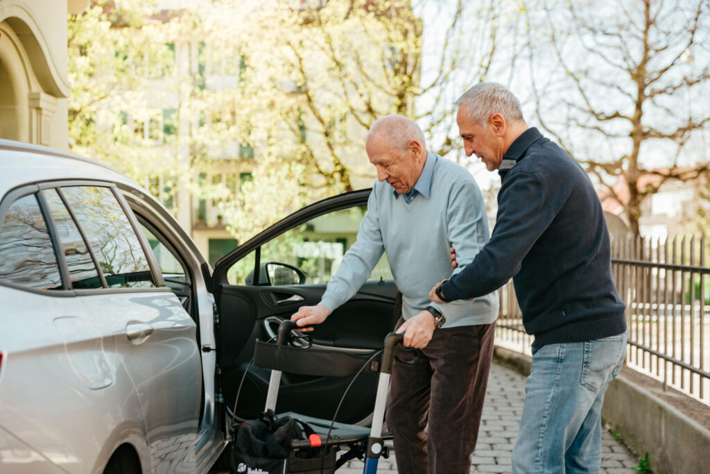 Un bénévole Transport Croix-Rouge aide son bénéficiaire à entrer dans la voiture.
