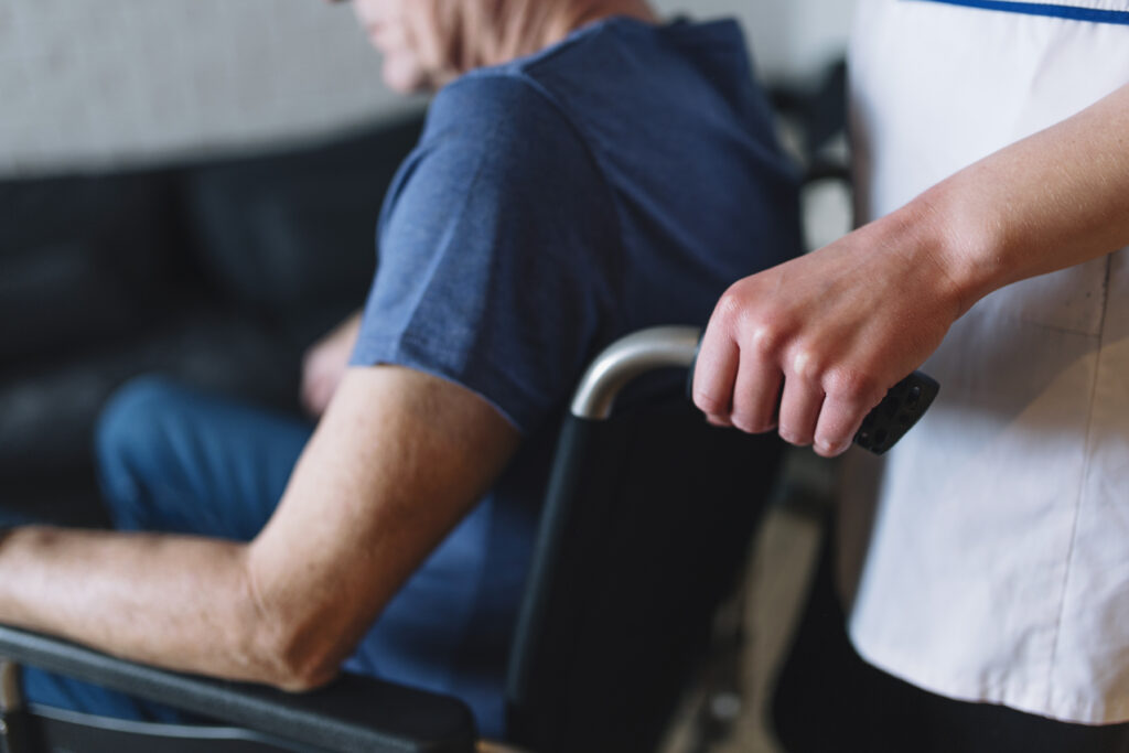Une AS aide un vieil homme en chaise roulante
